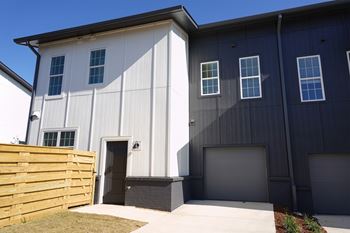 Townhouse building exterior with attached garage and fenced pet yard at Wesley Place Apartments in Birmingham, AL